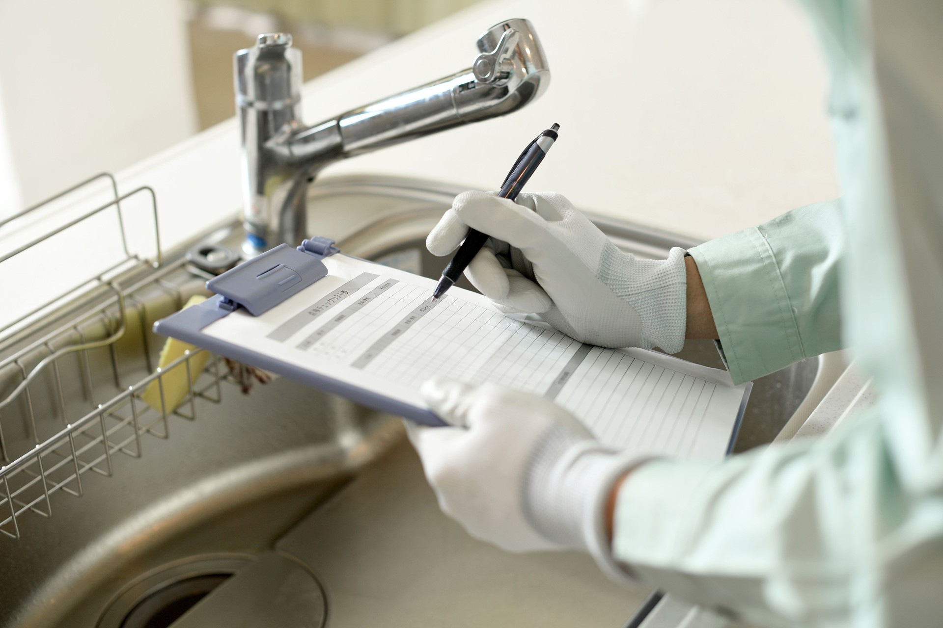 At hand of a worker inspecting the water supply in a home kitchen